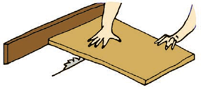 A worker's hand placed directly over the area of the wood where the saw will cut through from below.