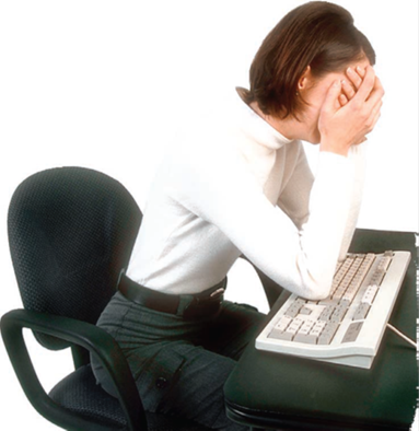Worker at her desk with head in heads and elbows on keyboard.