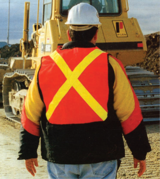 Un employé sur un chantier  - Image d'un employé sur un chantier. Il porte un gilet rouge et jaune. Il y a une grande croix jaune sur le dos du gilet. 