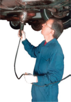 Un mécanicien répare une voiture - Image d'un mécanicien réparant une voiture. Il porte une combinaison bleue.